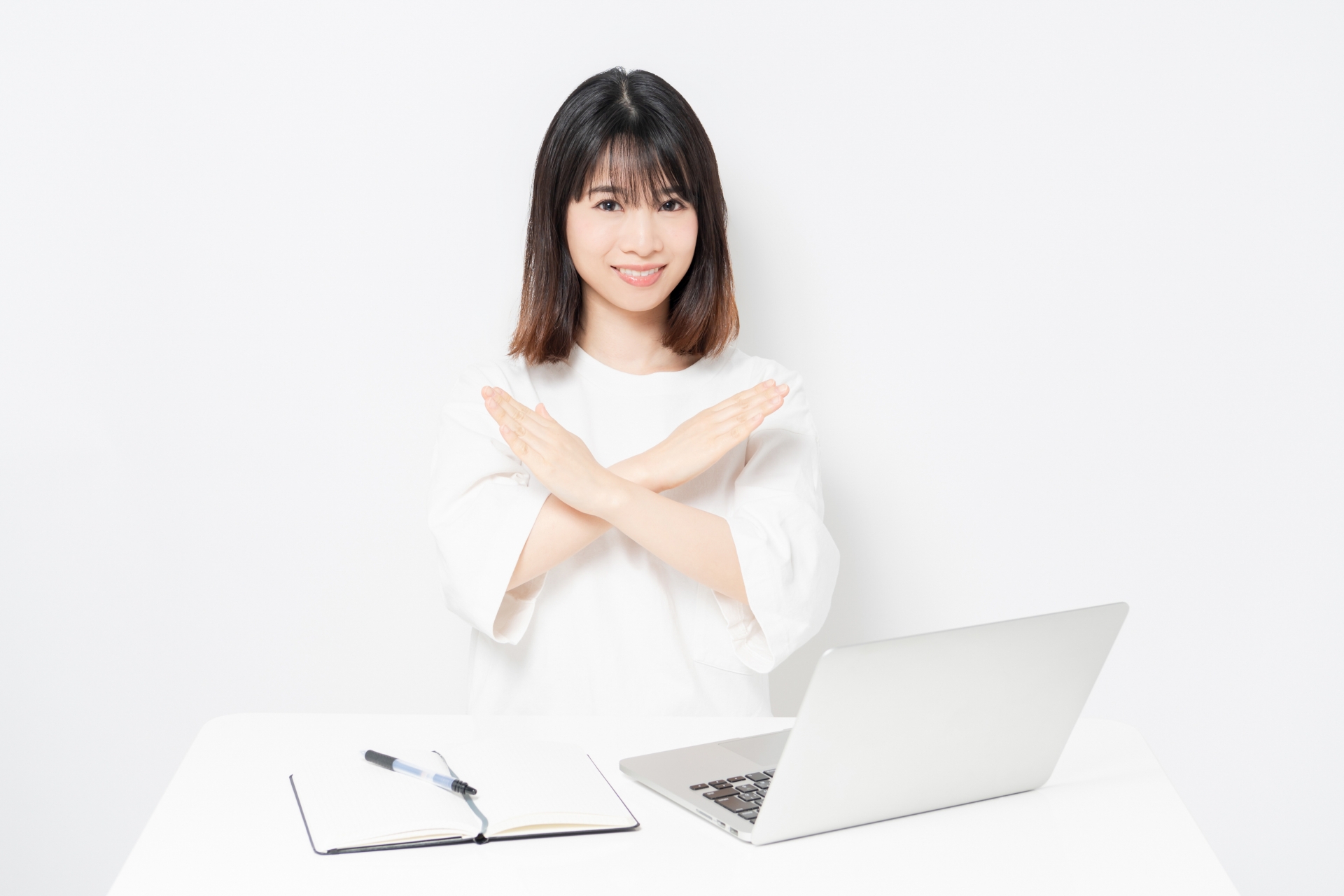 パソコンの前で、手でバツをしている女性