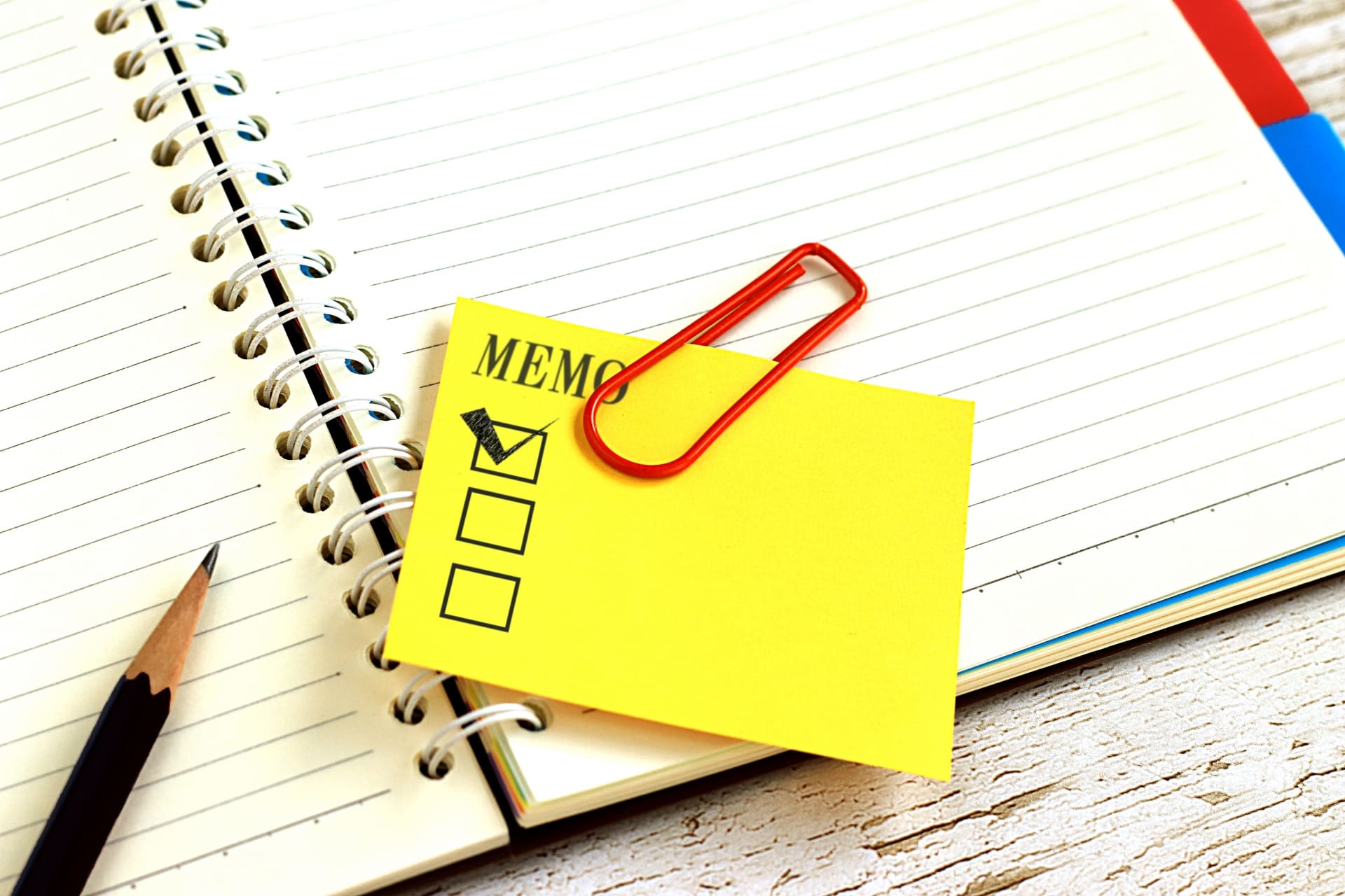 チェックマークが書かれたメモ帳と、ノートとペン